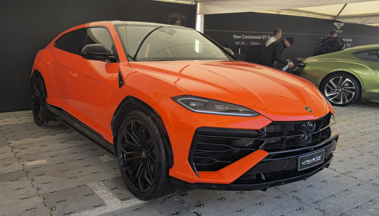 Lamborghini Urus SE laranja exposto num evento, visto de frente